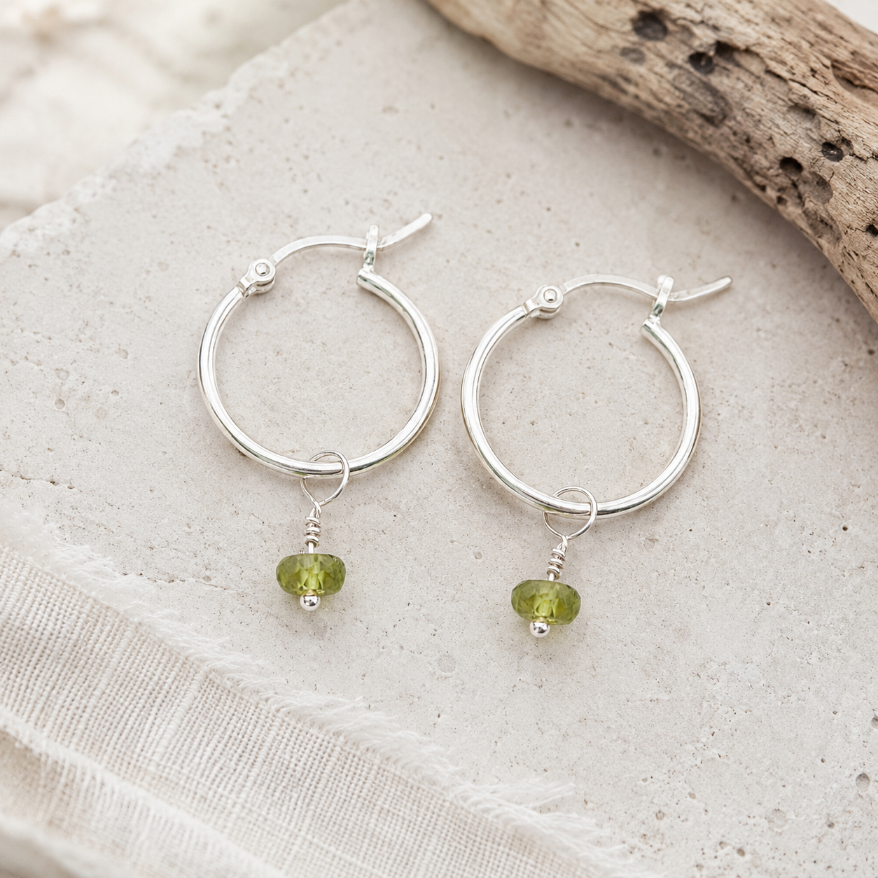 Peridot hoops laid flat on limestone with drift wood